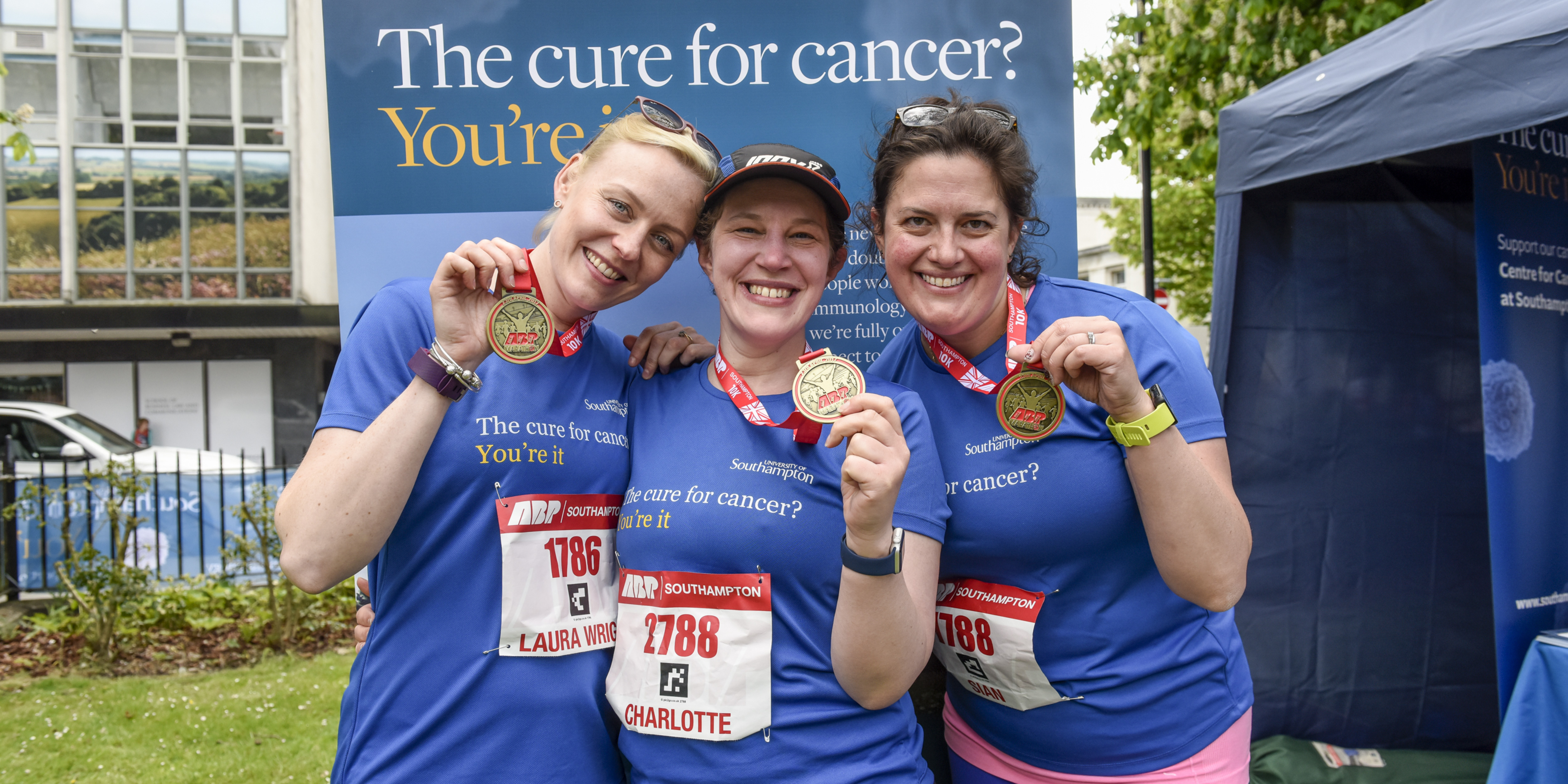 Three women holding up their medals after completing the Southampton Marathon